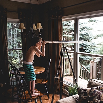 boy looking through a telescope