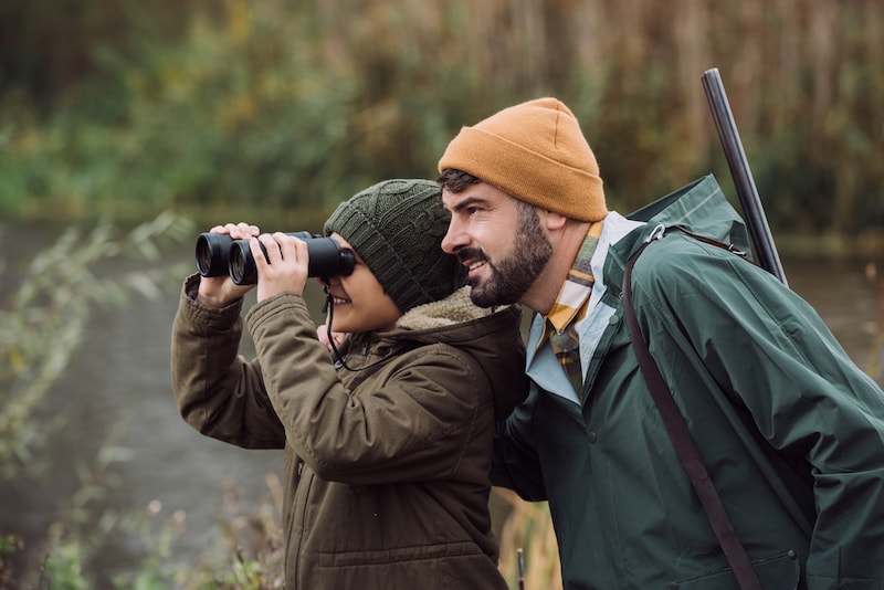 Vater und Sohn jagen mit Fernglas