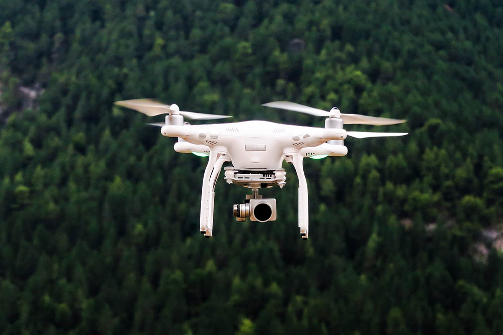 white drone camera mid-flight