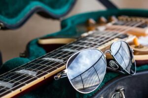 aviator sunglasses beside a guitar