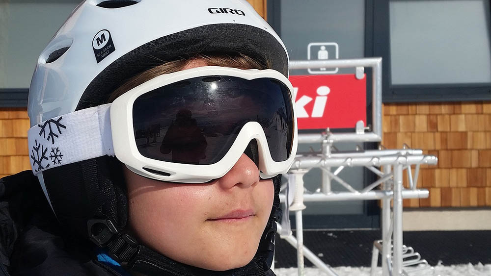 child wearing white ski goggles and helmet