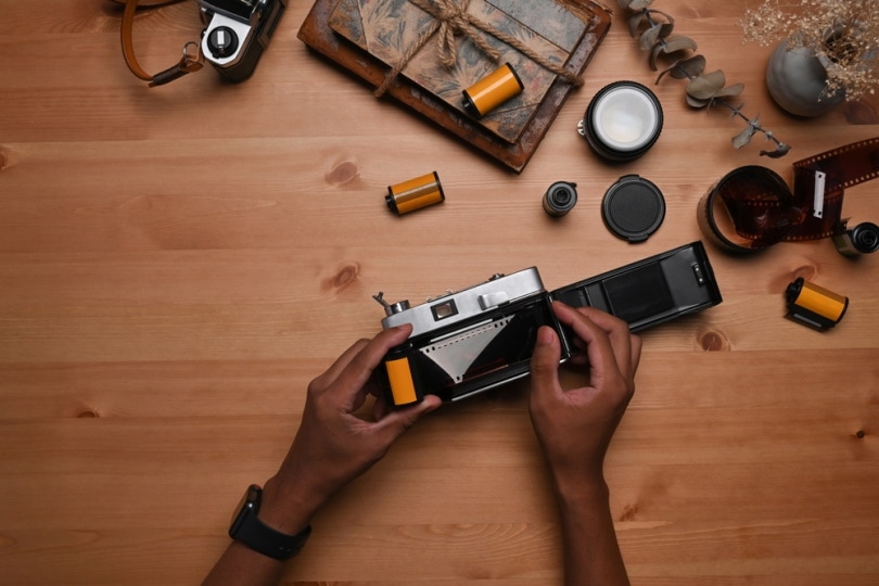 man putting film into camera