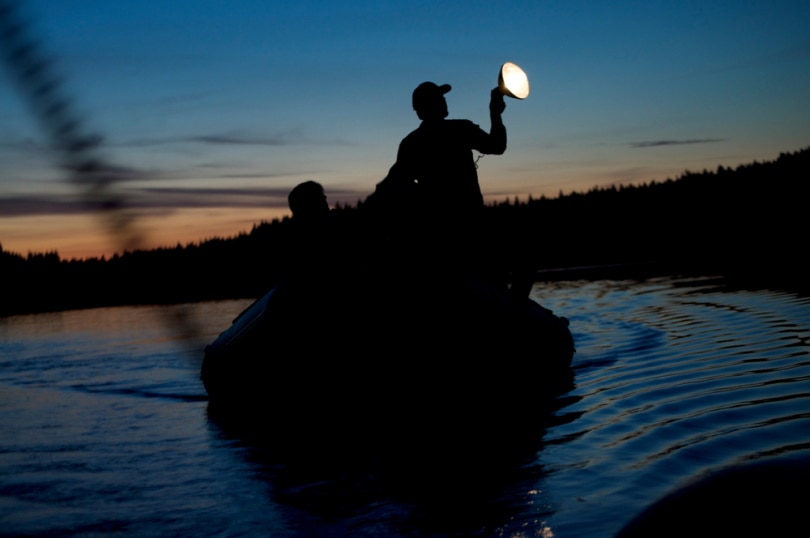 man riding a boat holding spotlight