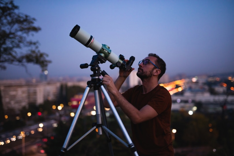 man watching stars using telescope