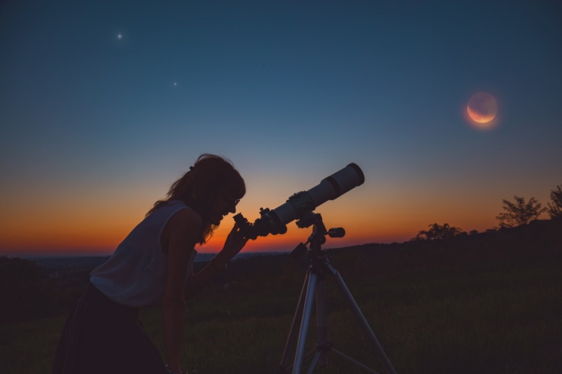 woman looking at lunar eclipse in the telescope