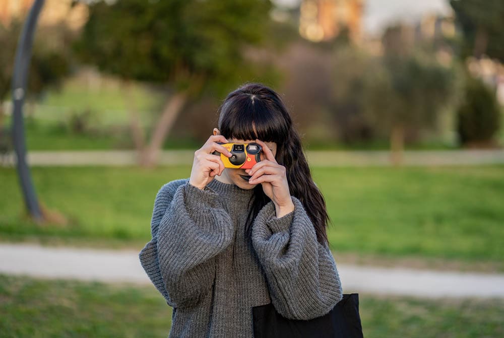 woman taking photo using kodak disposable camera