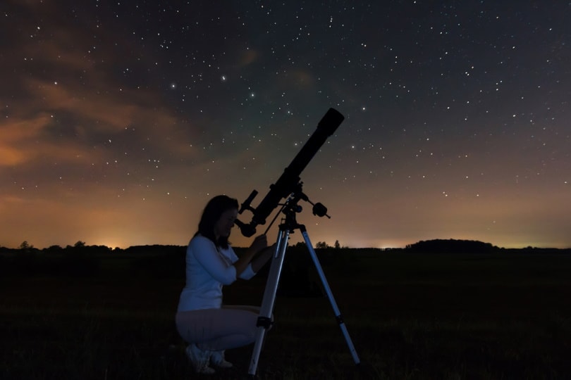 woman watching stars using telescope