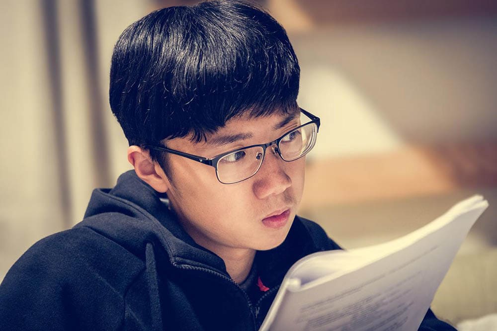 young man wearing eyeglasses studying in dim light