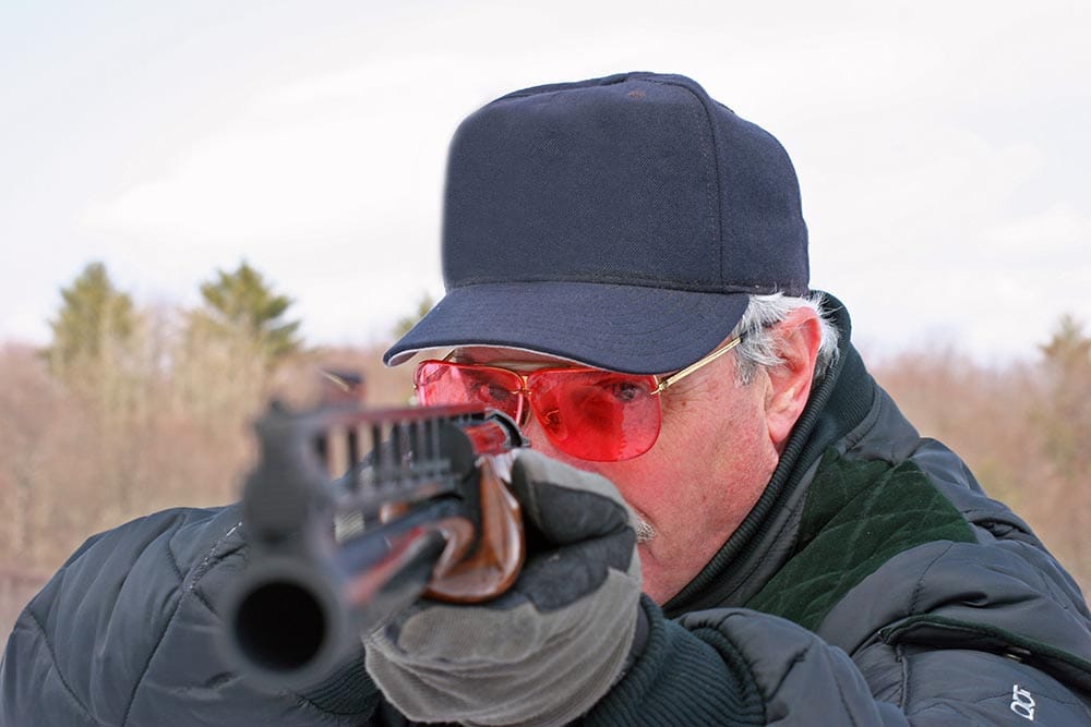 man with red shooting glasses pointing the gun