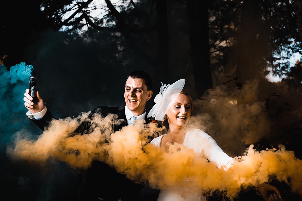 newlywed couple surrounded with colorful smoke