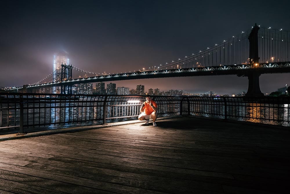 photo of a man in front of the brooklyn bridge
