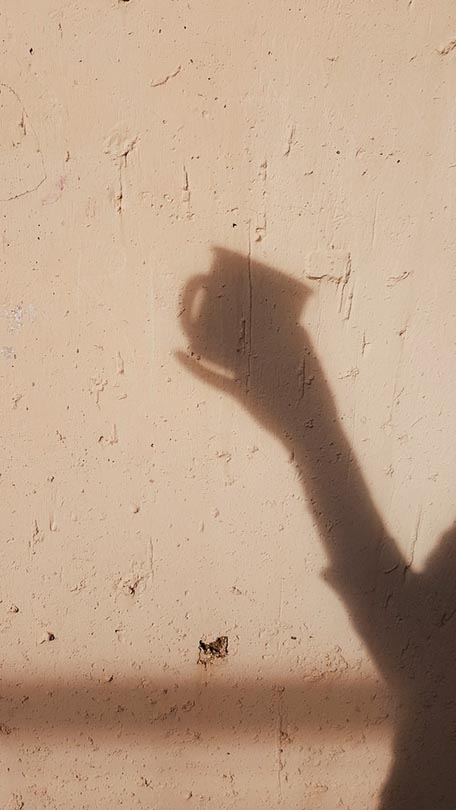shadow of a person holding a cup