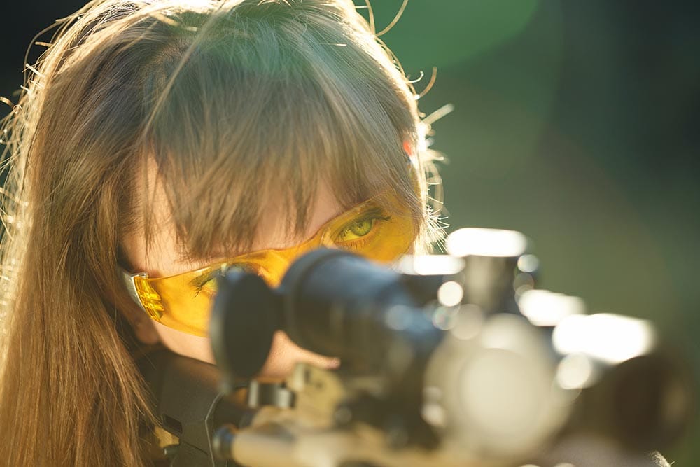 woman wearing yellow shooting glasses aiming the gun