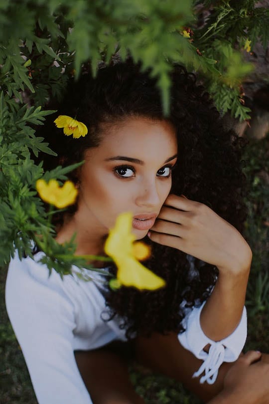 curly haired woman surrounded with flowers