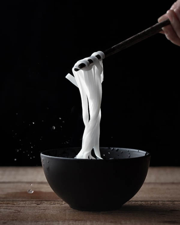 grabbing white noodles with chopsticks