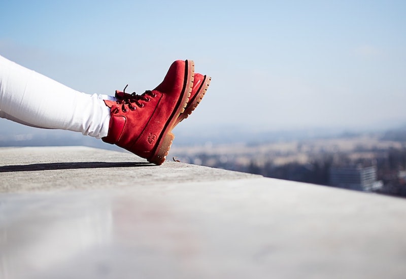 red boots on ledge of tall building over city