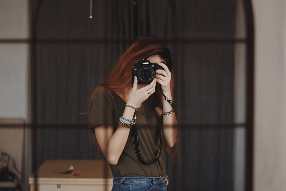 young woman taking self portrait in the mirror