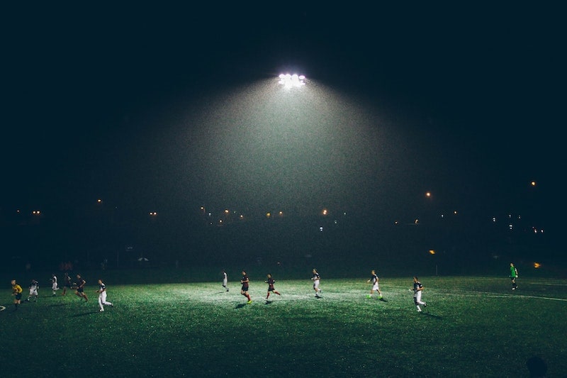 sports team running on field at night photography