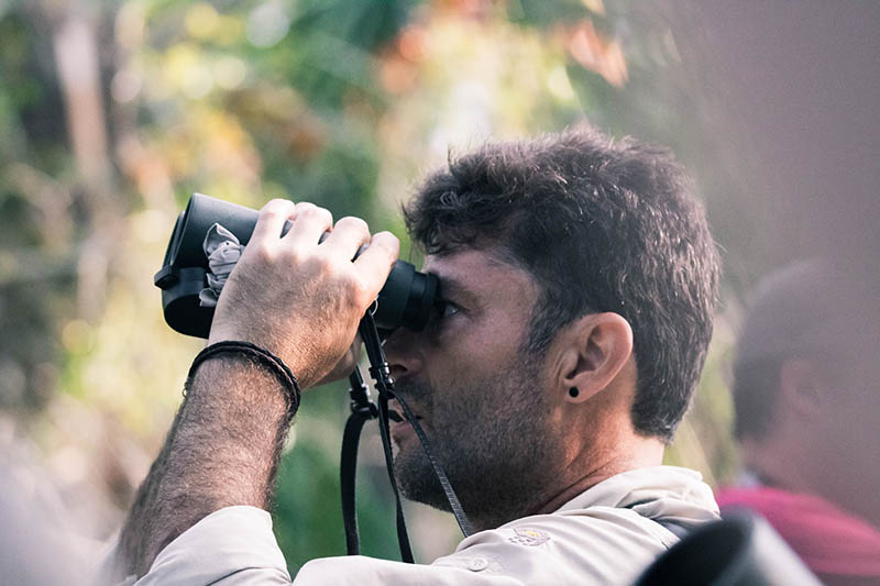 close up man using binoculars to spot birds