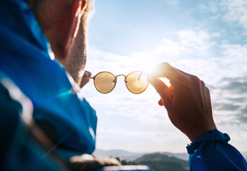 backpacker looking at bright sun through polarized sunglasses