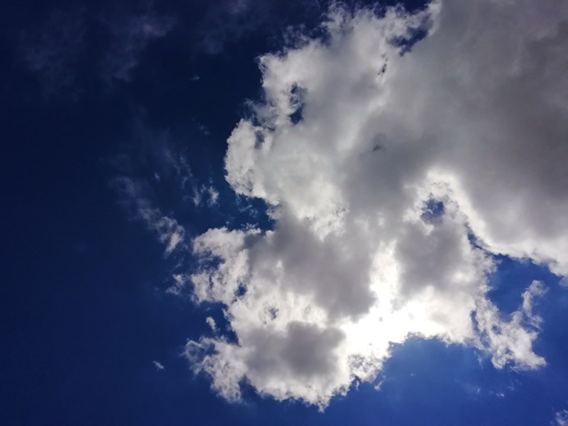 sunlight getting through the white clouds in the blue clear sky