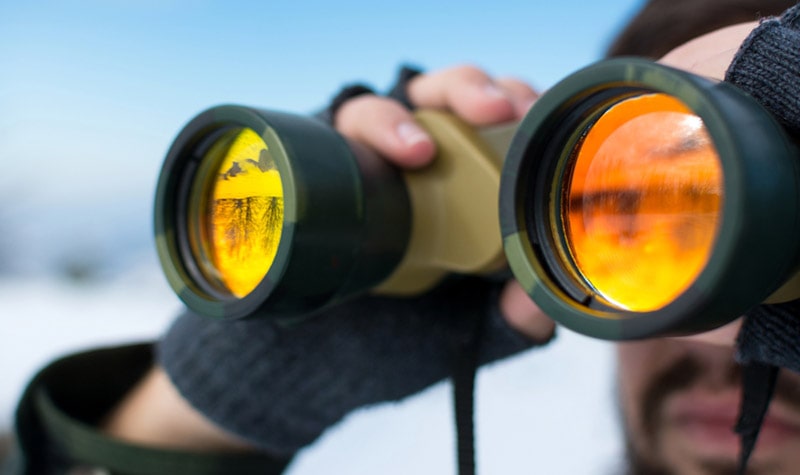 man using binoculars outside on a winter day
